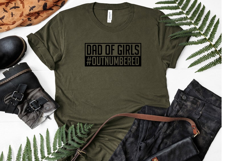 May include: A green t-shirt with the text "Dad of Girls #Outnumbered" printed on it.