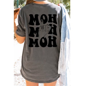 Pode incluir: Uma camiseta cinza-chumbo com um gr&aacute;fico preto da palavra "MOH" repetida tr&ecirc;s vezes com um dedo do meio em um anel entre as palavras.