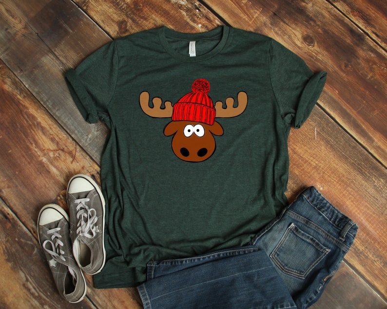 May include: A dark green t-shirt with a cartoon moose wearing a red knit hat with a white pom-pom.