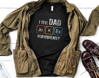 Könnte beinhalten: Ein schwarzes T-Shirt mit einer weißen Grafik, auf der "I tell Dad Jokes Periodically" steht, wobei das Wort "Jokes" mit den chemischen Symbolen für die Elemente Jo, K und Es ausgeschrieben ist.