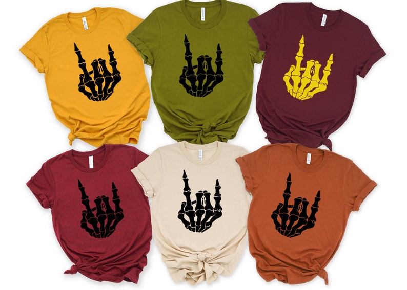 Puede incluir: Seis camisetas de manga corta en varios colores, como amarillo mostaza, verde oliva y burdeos. Cada camiseta presenta un gr&aacute;fico de mano de esqueleto negro en un gesto de rock and roll. Las camisetas est&aacute;n hechas de un material suave.
