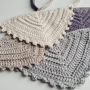 May include: Three crocheted wall hangings in different shades of gray, beige, and white. Each hanging is a half-circle shape with a scalloped edge.