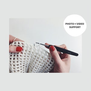 Puede incluir: Primer plano de una persona tejiendo un tejido de crochet blanco con un gancho de crochet negro. El gancho est&aacute; etiquetado como "4.00 mm".