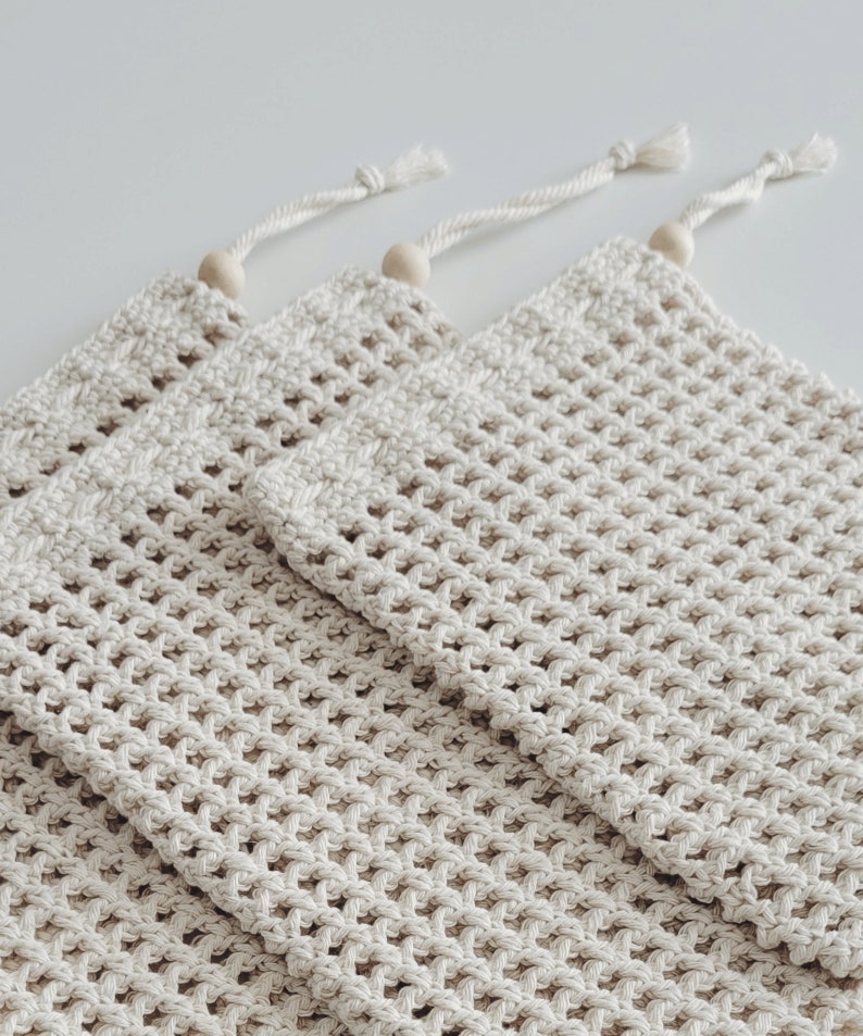 Puede incluir: Tres bolsas de malla de crochet beige con cuentas de madera en la parte superior de los cordones.