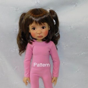 May include: A pink doll outfit with long sleeves and pants. The outfit has a round neckline and the word "Pattern" is printed on the front.