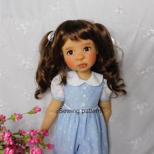 May include: A blue and white polka dot dress with a white collar and short sleeves. The dress has a white belt and is worn by a doll with brown hair and a light complexion. The text "Sewing pattern" is visible on the dress.