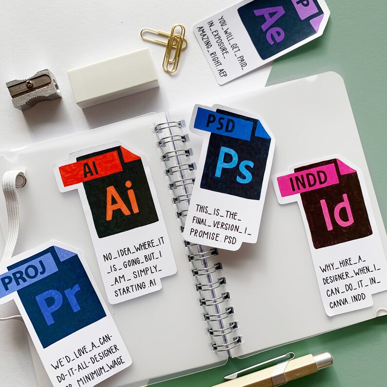 K&ouml;nnte beinhalten: Eine Sammlung bunter Aufkleber mit verschiedenen Software-Symbolen. Die Aufkleber haben die Form von Ordnern und enthalten den Text "Ai", "Ps", "Id", "Pr" und "Ae". Jeder Aufkleber hat eine kurze, humorvolle Bildunterschrift &uuml;ber das Softwareprogramm.