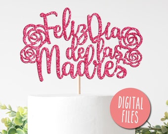 May include: Pink glitter cake topper with the text "Feliz Dia de las Madres" and floral accents. The topper is on top of a white cake.