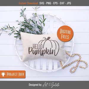 May include: A white pillow with the text "HELLO PUMPKIN" and a brown outline of a pumpkin on it. The pillow is sitting on a white wicker basket with a sprig of greenery.