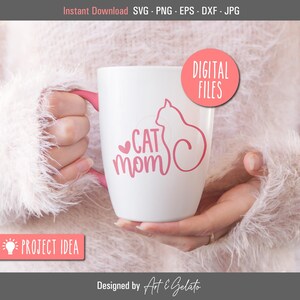 May include: White ceramic mug with a pink outline of a cat and the text "CAT MOM" in pink lettering.