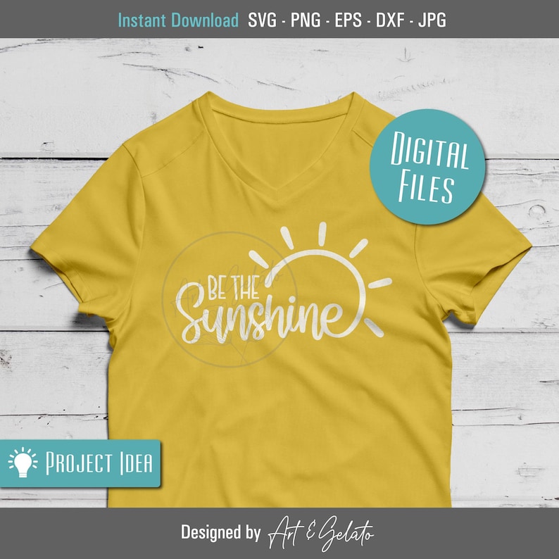May include: A yellow t-shirt with a white sun graphic and the text "Be the Sunshine" on the front. The shirt is on a wooden surface.