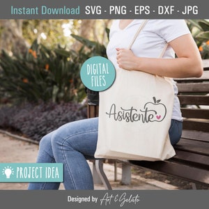 May include: A white tote bag with the text "Asistente" and a red apple with a pink heart on it. The bag is being held by a person wearing a white shirt and blue jeans.