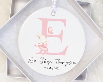 May include: A white ceramic ornament with a pink letter E and a pink bunny holding a pink balloon. The ornament has the text "Eva Skye Thompson 9th May 2022" printed on it.