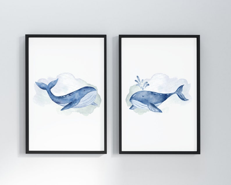 May include: Two framed watercolor prints featuring blue whales. One whale is swimming, the other is spouting water. Each whale is set against a soft, watercolor cloud background. The frames are black, and the art is on white paper.