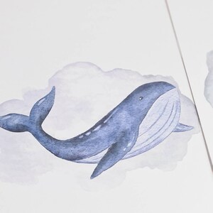 May include: Watercolor illustration of a blue whale swimming in a lavender cloud. The whale has a detailed design with a white belly and a curved tail. The artwork is on a white background.