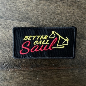 May include: Black embroidered patch with yellow and red stitching. The patch reads "Better Call Saul" with a yellow scale design.