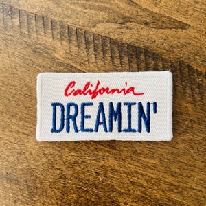 May include: White embroidered patch with red text that says "California" and blue text that says "Dreamin'"