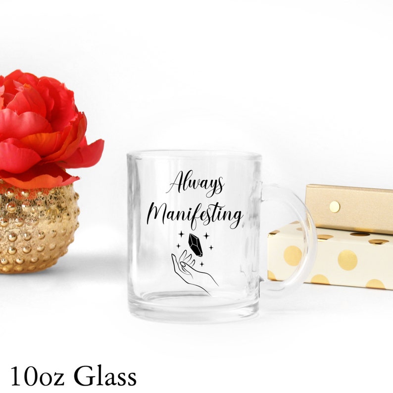 May include: A clear glass 10oz mug with a black design that says "Always Manifesting" with a hand holding a crystal and stars.