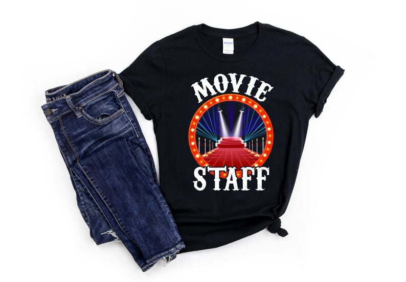 May include: Black t-shirt with white text that reads "Movie Staff" and a red carpet with spotlights graphic.