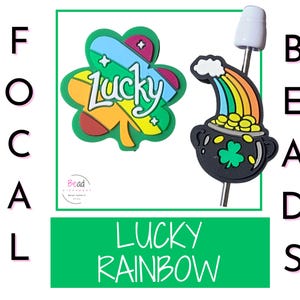 Puede incluir: La imagen presenta dos cuentas con temática del Día de San Patricio. Una es un trébol verde con la palabra "Lucky" y la otra es una olla de oro con un arcoíris. También son visibles las palabras "Focal Beads" y "Lucky Rainbow".