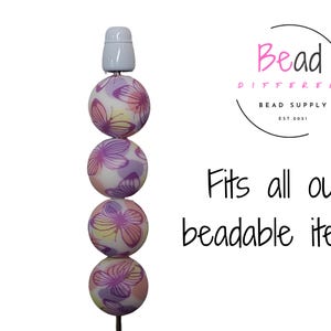 May include: A stack of five colorful beads with a butterfly pattern. The beads are strung on a white cord and have a white cap on top. The text "Fits all our beadable items" is written below the beads.