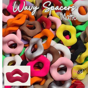 May include: A variety of colorful, wavy, matte plastic spacers. The spacers are in various shapes, including circles, ovals, and lips. The text "Wavy Spacers Matte" is visible in the image.