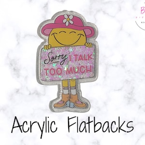 May include: Acrylic flatback featuring a smiling yellow character wearing a pink hat and holding a sign that reads "Sorry I talk too much." The sign has pink glitter and the character is wearing boots.