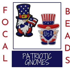 Peut inclure: Deux breloques de chaussures de gnome patriotiques. Le gnome de gauche tient un petit drapeau américain. Le gnome de droite tient un cœur avec "USA" écrit dessus. Les deux gnomes portent des chapeaux rouge, blanc et bleu.