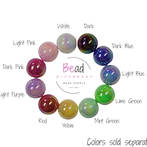 Puede incluir: Una colecci&oacute;n de cuentas de vidrio iridiscentes en varios colores, incluyendo blanco, oscuro, rosa claro, azul oscuro, rosa oscuro, p&uacute;rpura claro, rojo, amarillo, verde menta y verde lima. El texto "Bead Different" est&aacute; en el centro. Colores se venden por separado.