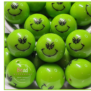 May include: Bright green acrylic beads with a cartoon face design. The beads have a glossy finish and a black smiling face with a furrowed brow. The word "Acrylic" is written vertically in green letters on the left side of the image. The beads are from Bead Supply.