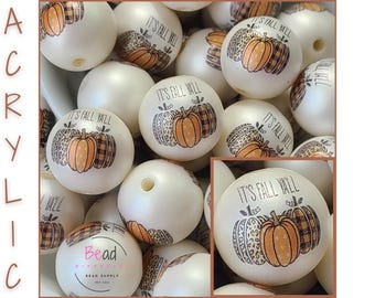 May include: A collection of round white acrylic beads featuring a printed graphic of three pumpkins with leopard and plaid patterns, accompanied by the text IT'S FALL Y'ALL. The word ACRYLIC is printed vertically on the left side.