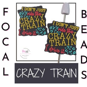 Puede incluir: Dos dijes de cuentas negras con el texto "I DON'T JUST ride the CRAZY TRAIN I drive it" en amarillo, rojo y turquesa. También hay un alfiler de cuentas plateado con una cuenta gris en la imagen. La palabra "CRAZY TRAIN" está escrita en blanco.