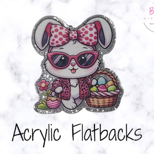 以下が含まれることがあります： サングラスとリボンをつけた漫画のウサギが、イースターエッグのバスケットと花を持っているアクリル製のフラットバック。ウサギはピンクのヒョウ柄のジャケットを着ています。画像にはキラキラしたボーダーがあります。