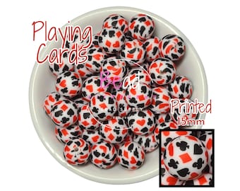 May include: A bowl of 15mm white silicone beads with a red, black, and white playing card design. The beads are printed with playing card suits and numbers. The text "Playing Cards Printed 15mm" is visible on the image.