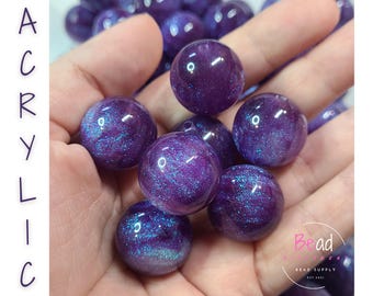 Puede incluir: Una colección de cuentas acrílicas redondas de color morado intenso con un acabado de purpurina brillante. Las cuentas tienen una superficie brillante con destellos azules y morados incrustados. La palabra ACRYLIC está impresa verticalmente a la izquierda y el logotipo de Bead Bead Supply está en la esquina inferior derecha.