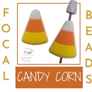 Puede incluir: Dos cuentas con forma de maíz dulce con rayas blancas, naranjas y amarillas. Las cuentas están sobre un fondo blanco con el texto "Focal Beads" y "Candy Corn" en letras doradas.
