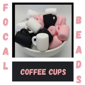 May include: A bowl filled with colorful silicone coffee cup beads. The beads are in pink, white, and black. The beads are shaped like coffee cups with handles.