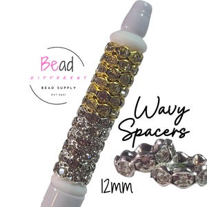 May include: A white pen-shaped bead supply with gold and silver wavy spacers. The image includes the text "Wavy Spacers" and "12mm". The logo for "Bead Different Bead Supply" is also visible.