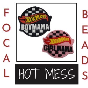 Puede incluir: Dos dijes para zapatos con el texto "Hot Mess", "Boymama" y "Girlmama". Los dijes son negros y rosas con un patrón de cuadros y un diseño de llama.