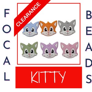 May include: A collection of six colorful cat-shaped focal beads. The beads are in shades of blue, orange, gray, green, purple, and pink. The word "KITTY" is in white letters on a red background. The word "CLEARANCE" is on a red diagonal banner.