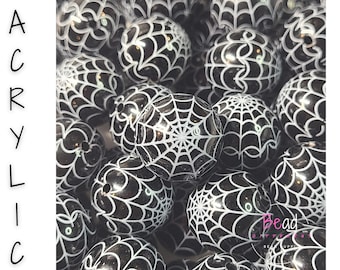May include: A collection of round black acrylic beads featuring a white spider web pattern printed on the surface. The word ACRYLIC is printed vertically in black on the left side, and the text Bead DIFFERENT is visible in the bottom right.