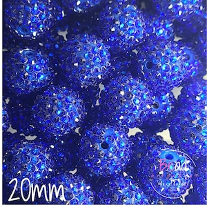 May include: A collection of sparkling blue beads, each approximately 20mm in diameter. The beads are covered in small, reflective crystals, creating a dazzling effect. They are a deep blue colour and have a hole for threading.
