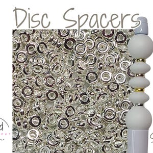May include: Silver disc spacers, 6mm in size, are shown in a pile. The spacers are a popular jewelry making supply.