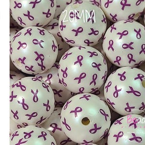 May include: A collection of 20mm acrylic beads featuring a white pearlized finish with a repeating pattern of purple awareness ribbons. The word ACRYLIC is printed vertically on the left side, and the text Bead Supply is visible at the bottom.