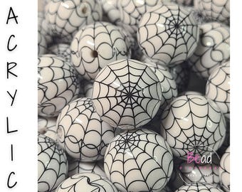 May include: A collection of round white acrylic beads featuring a black spiderweb pattern printed on the surface. The word ACRYLIC is printed vertically in black on the left side, and the text Bead Supply is visible in the bottom right corner.