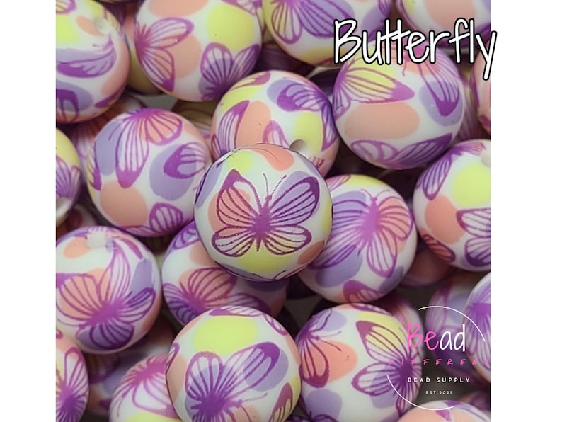 May include: A close-up of a collection of colorful silicone beads with a butterfly pattern. The beads are white with pink, purple, and yellow accents. The beads are arranged in a pile, and the word "Butterfly" is written in pink letters at the top of the image.