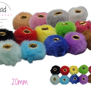 May include: A collection of round, fuzzy pom-pom beads in various colors, each featuring a central gold-toned metal grommet. The text "Bead Different Bead Supply" and "20mm" are visible. These soft, spherical beads come in shades including black, red, yellow, green, blue, purple, pink, and brown.