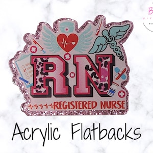 May include: A Registered Nurse acrylic flatback with pink glitter edges. The design includes a heart with a heartbeat, wings, a caduceus, and the letters "RN" in pink with a leopard print pattern. The words "REGISTERED NURSE" are also included.