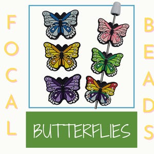 May include: Six colorful butterfly beads on a white string. The beads are in the following order: light blue, pink, yellow, green, purple, and rainbow. The beads are all about 1 inch in diameter. The string is about 6 inches long. The beads are labeled "Focal Butterflies Beads".