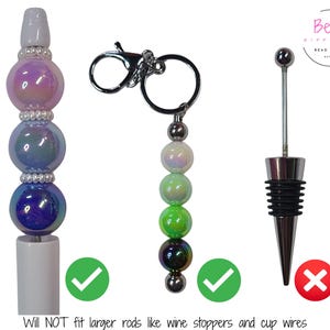Puede incluir: Una colecci&oacute;n de accesorios con cuentas, que incluye un bol&iacute;grafo, un llavero y un tap&oacute;n de vino. El bol&iacute;grafo y el llavero presentan cuentas iridiscentes en tonos morados, verdes y azules. El tap&oacute;n de vino es plateado y negro. El texto de la imagen dice "Will NOT fit larger rods like wine stoppers and cup wires."